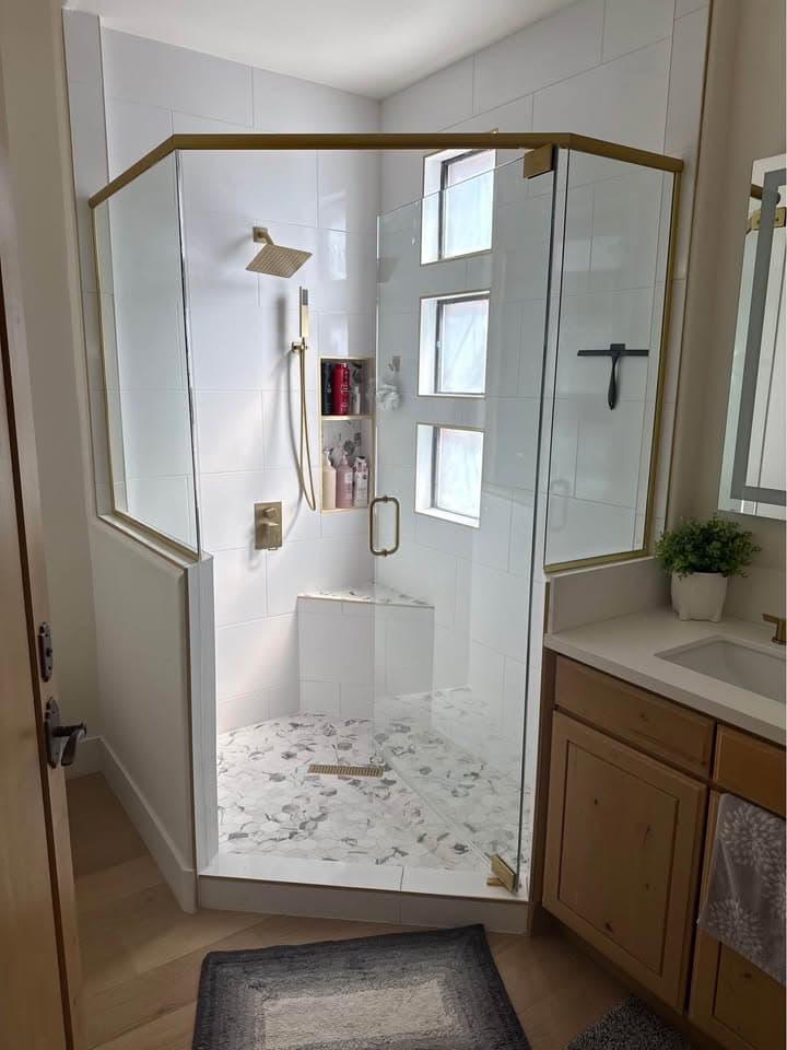 Neo-angle glass shower enclosure with brushed gold hardware